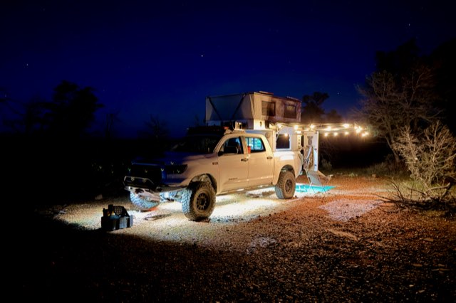 Truck camper lit up under a night sky