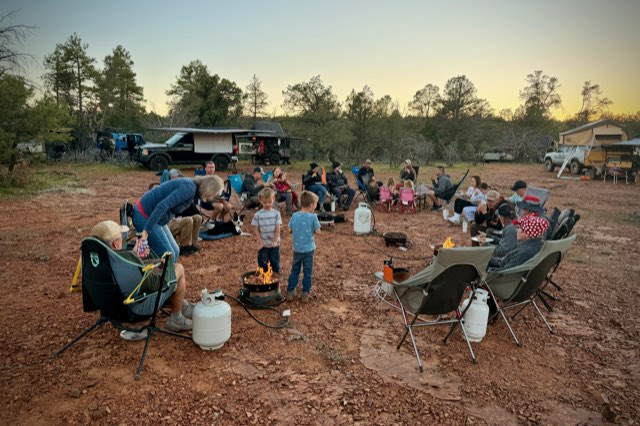 Everyone gathered in camp chairs around the fire at dusk